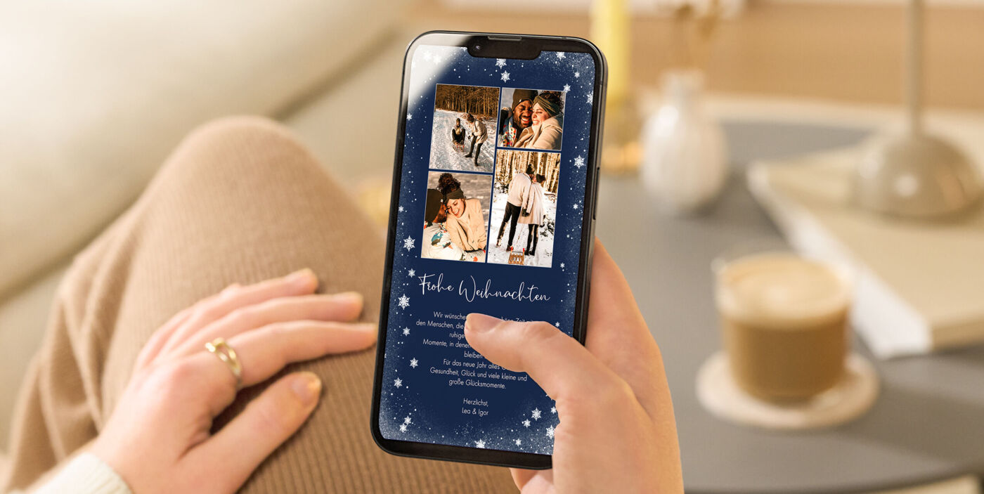 Eine Hand hält ein Smartphone mit einer CEWE-Grußkarte zu Weihnachten.